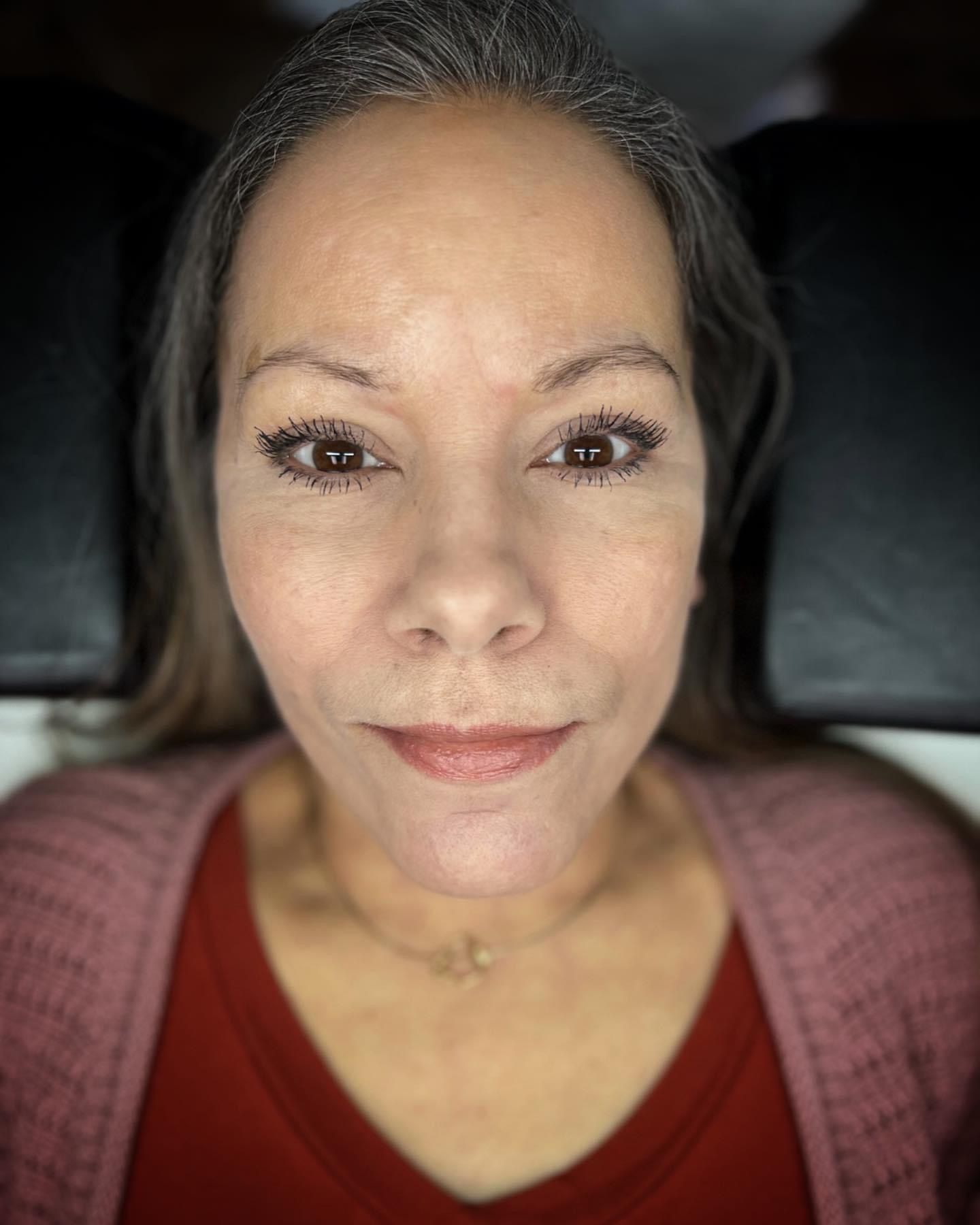 A close up of a woman 's face wearing a pink sweater and a red shirt.