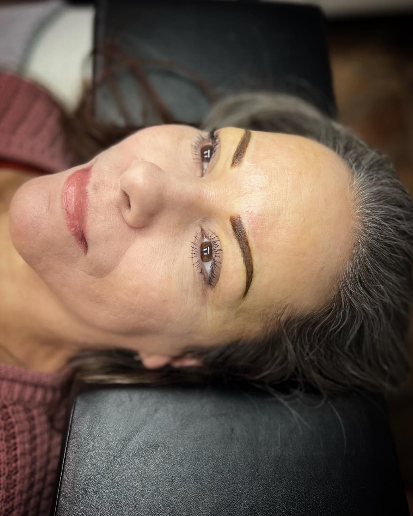 A close up of a woman laying on a bed with her eyes closed.