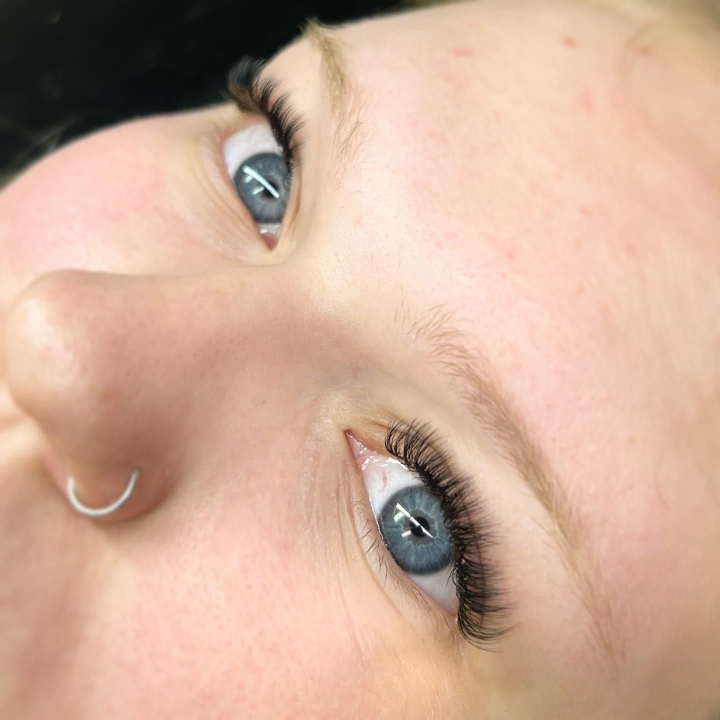 A close up of a woman 's face with blue eyes and long eyelashes.