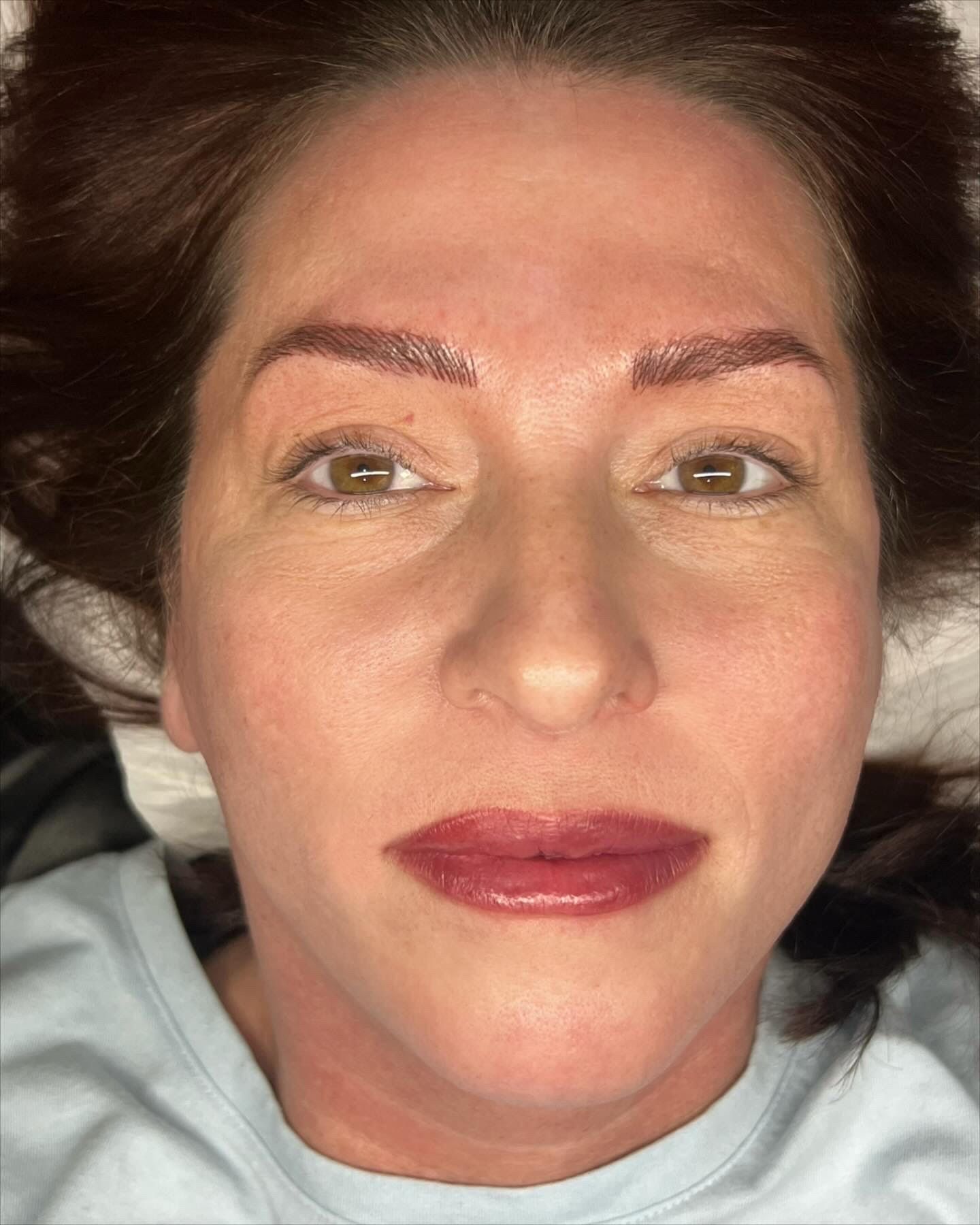 A close up of a woman 's face with red lips and eyebrows.