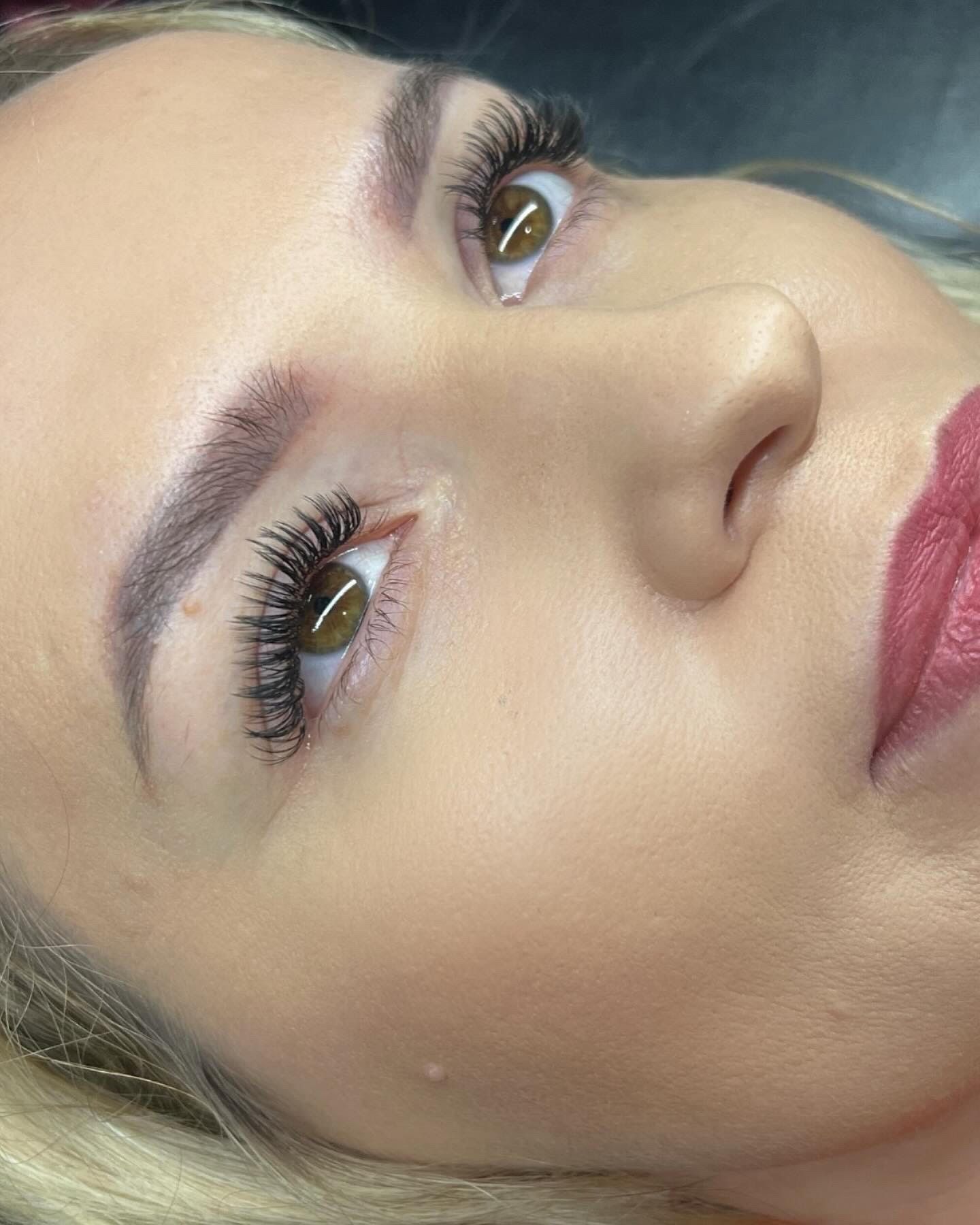 A close up of a woman 's face with long eyelashes and red lips.