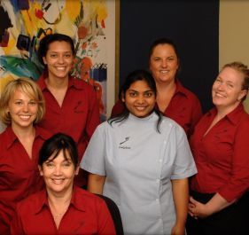 A group of women in red shirts are posing for a picture