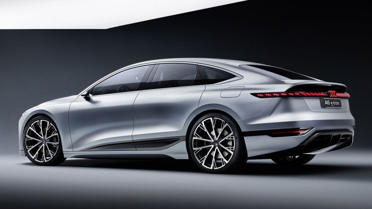 Een zilverkleurige Audi A6 e-tron staat tegen een donkere wand