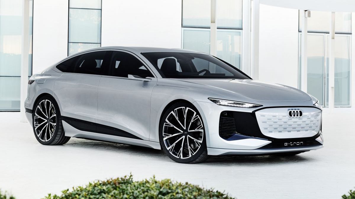 Een zilverkleurige Audi A6 e-tron staat geparkeerd voor een gebouw