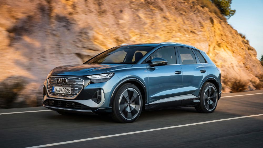 Een blauwe Audi Q4 e-tron rijdt op de weg langs een bergwand
