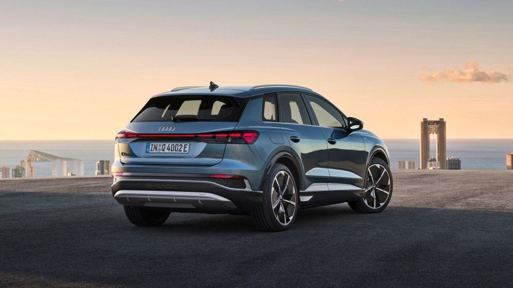 Een blauwe Audi Q4 e-tron staat geparkeerd in de buurt van een zee of oceaan