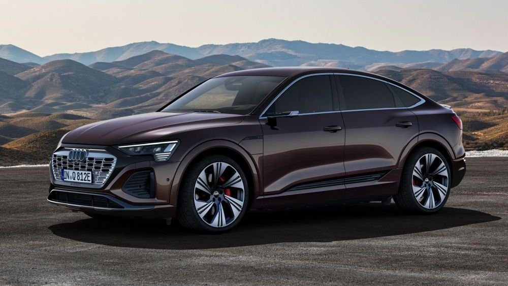 Een bruine Audi Q8 Sportback 55 e-tron quattro rijdt door een berglandschap
