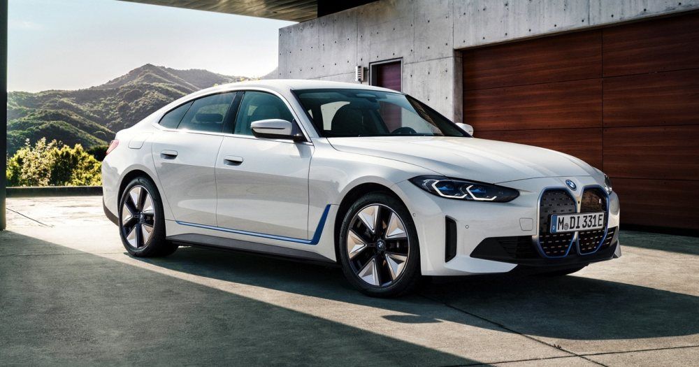 Een witte BMW i4 eDrive35 staat voor een houten garagedeur