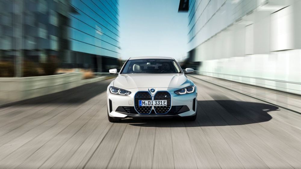 A white bmw is driving down a city street.