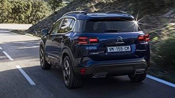 Een blauwe Citroen c5 Aircross rijdt in een bergachtige omgeving