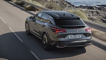 Een C5 X rijdt in ruig landschap in de buurt van een oceaan