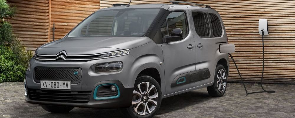 Een grijze Citroën e-Berlingo staat bij een muur van schrootjes en wordt geladen