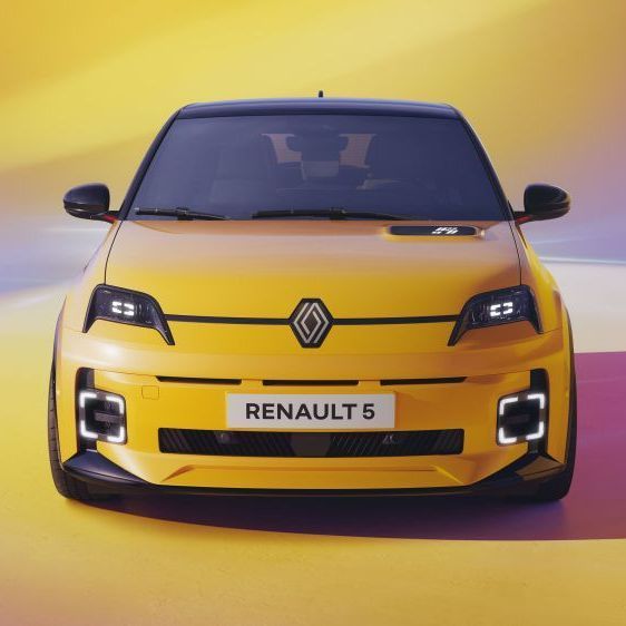 Een gele elektrische Renault 5 staat tegen een gele achtergrond