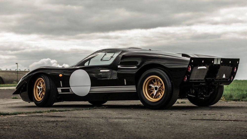 Een zwarte sportwagen Everrati Ford GT40 staat langs de kant van de weg geparkeerd.