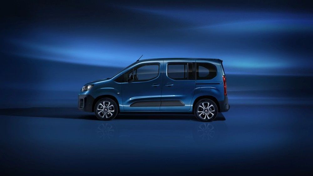 Een blauwe Fiat e-Doblo busje staat geparkeerd op een donkerblauwe achtergrond