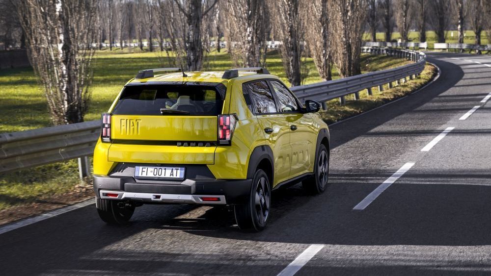 Een gele Fiat Grande Panda rijdt aan de linkerkant van een weg met vangrails