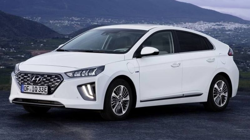 Hyundai Ioniq plug-in hybride staat in de bergen met een stad op de achtergrond