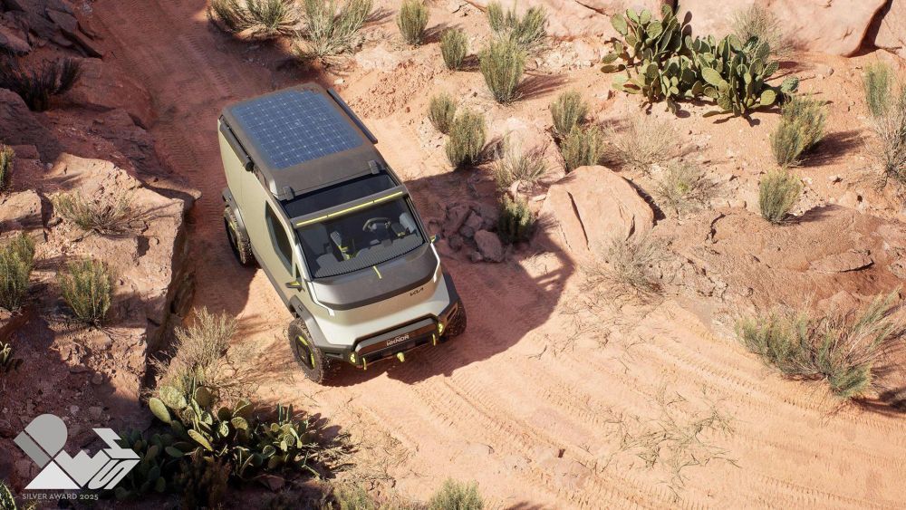 Een KIA PV5 met zonnepaneel rijdt off the road over een zandweg in een woestijn