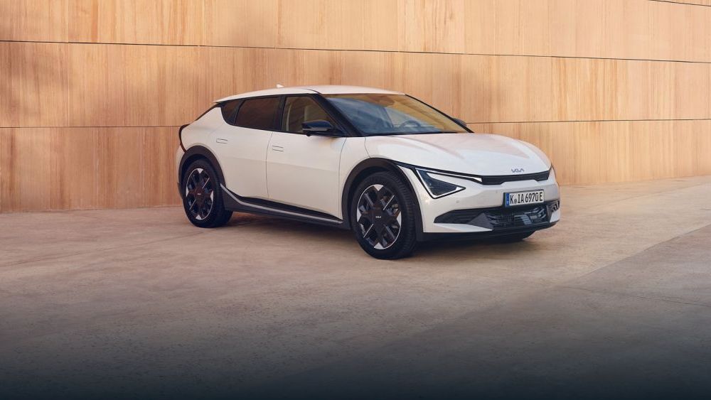 Een witte KIA EV6 model uit 2024 staat voor een muur van grote gele bouwstenen