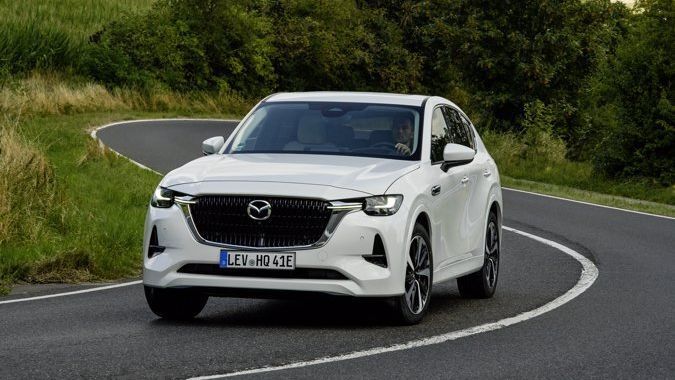 Een witte Mazda CX-60 Takumi rijdt over een bochtige weg