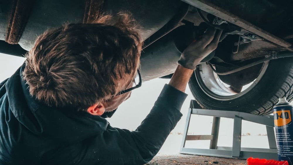 Een man voert onderhoud uit aan de bodemplaat van een auto