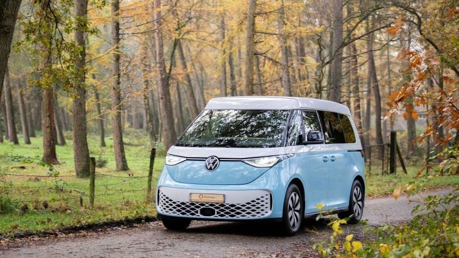 Een elektrische campervan Outbase ID.Buzz rijdt door het bos