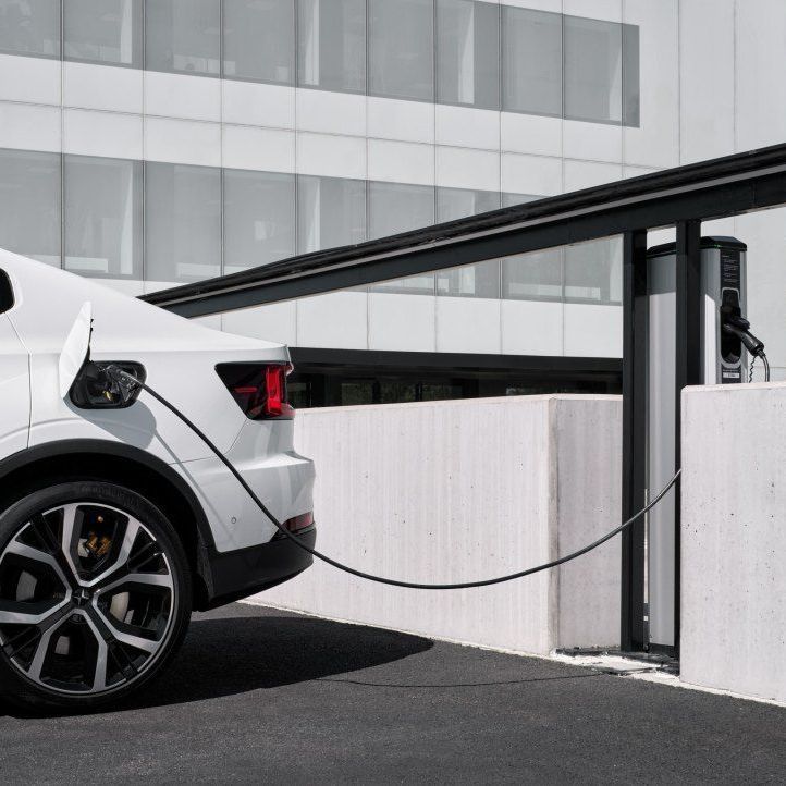 Een Polestar 2 staat bij een kantoor aan een elektrische laadpaal