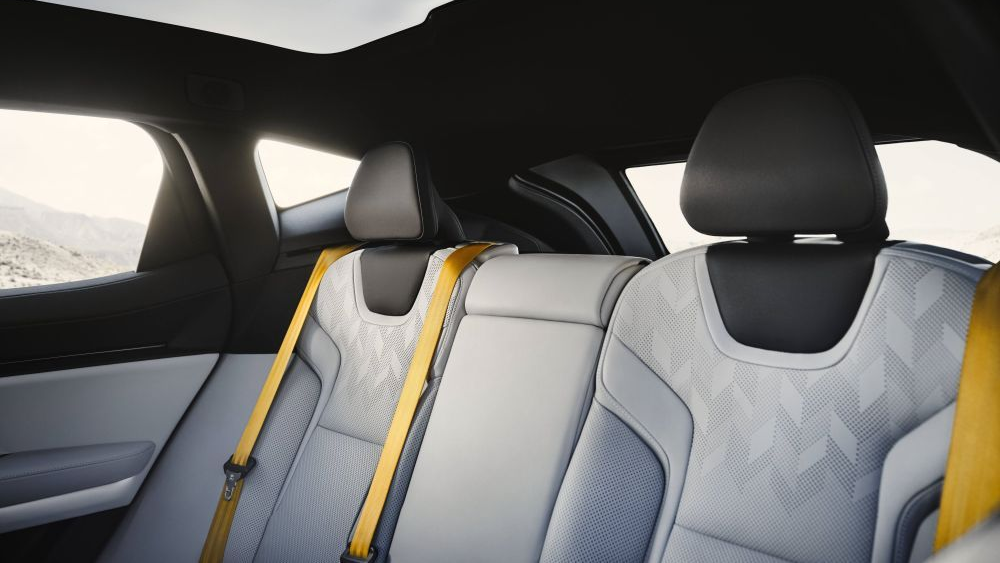 Rear interior Polestar 3 seats with white upholstery, yellow seatbelts, and a scenic background.