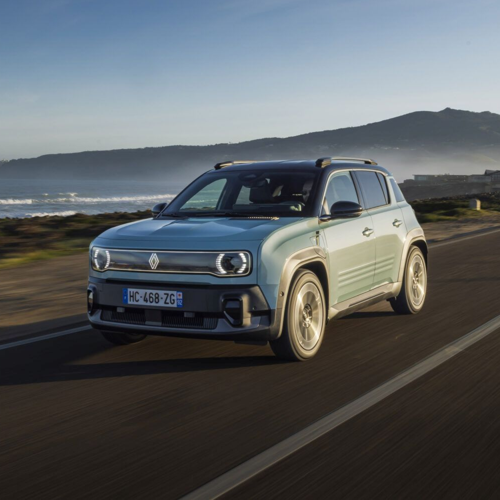 Een lichtblauwe Renault 4 E-Tech electric rijdt langs de kust