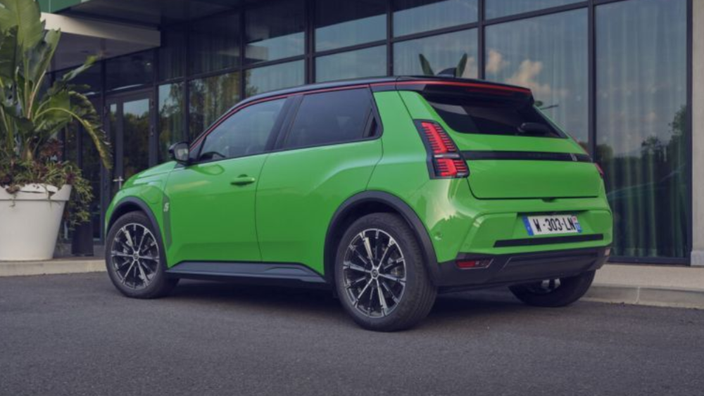 Een fel groene Renault 5 E-Tech staat geparkeerd voor een gebouw met een gevel van glas