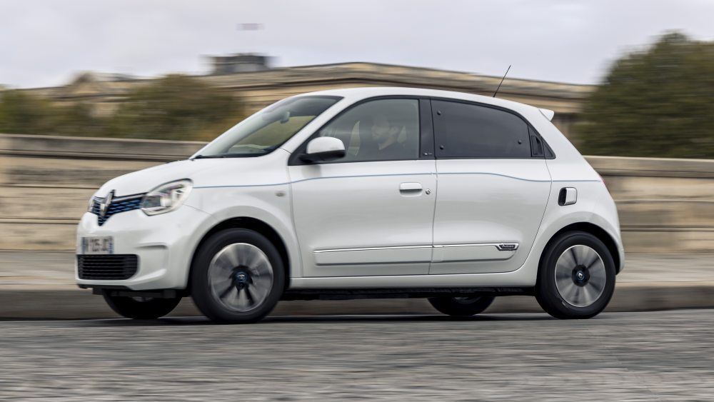 Een witte Renault Twingo Electric rijdt met snelheid over een weg