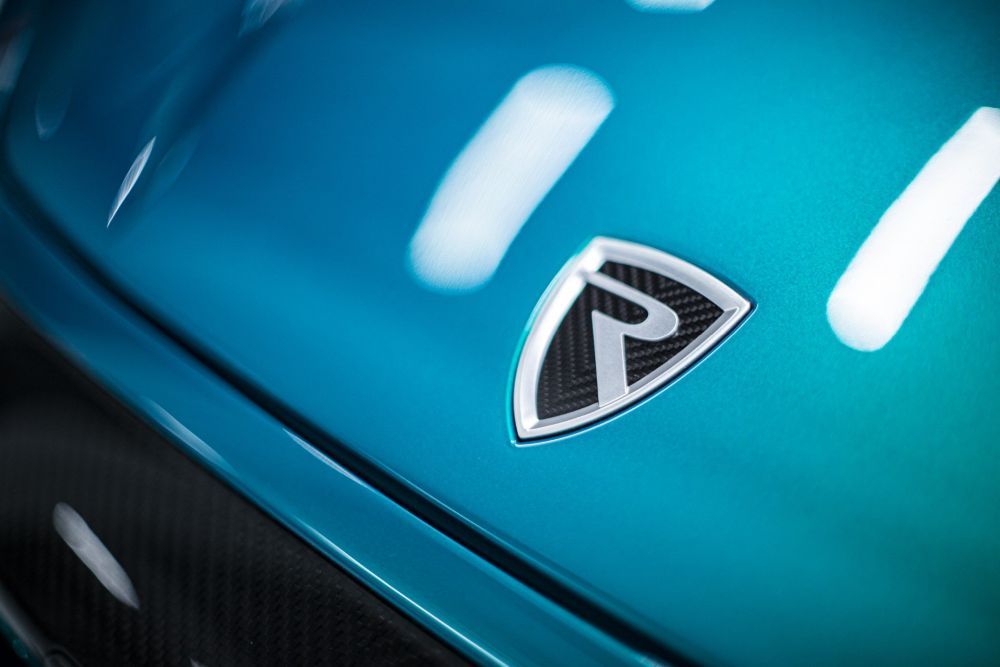 Een close-up van het embleem van een blauwe elektrische Rimac Nevera