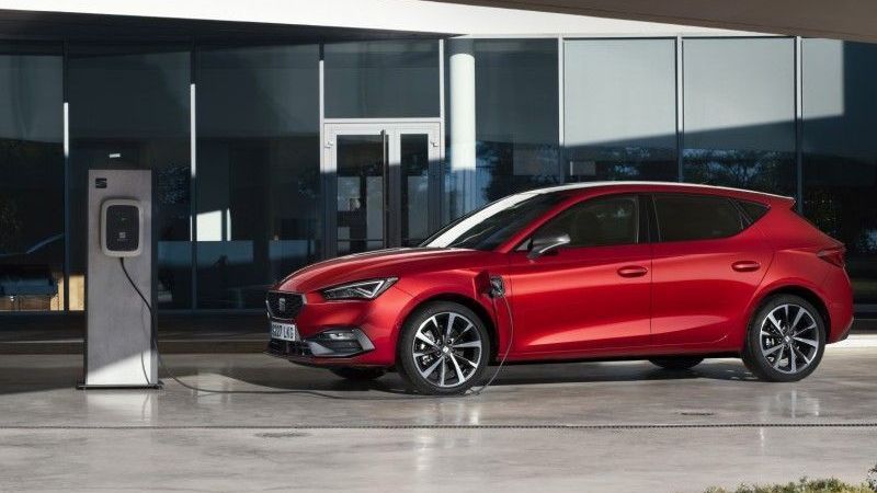 Een rode Seat Leon hybride uit 2021 staat bij een laadstation