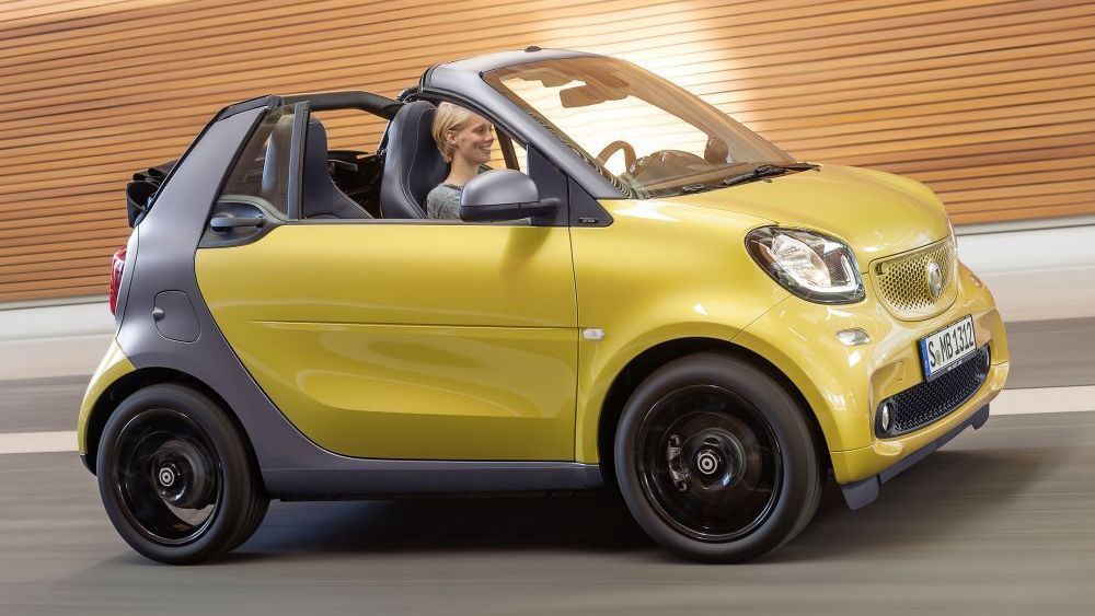 Een vrouw rijdt in een donkergele Smart EQ Fortwo cabrio