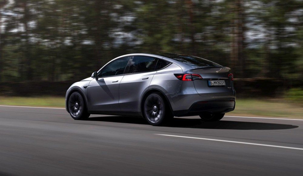 Een Tesla Model Y rijdt over een snelweg langs bomen