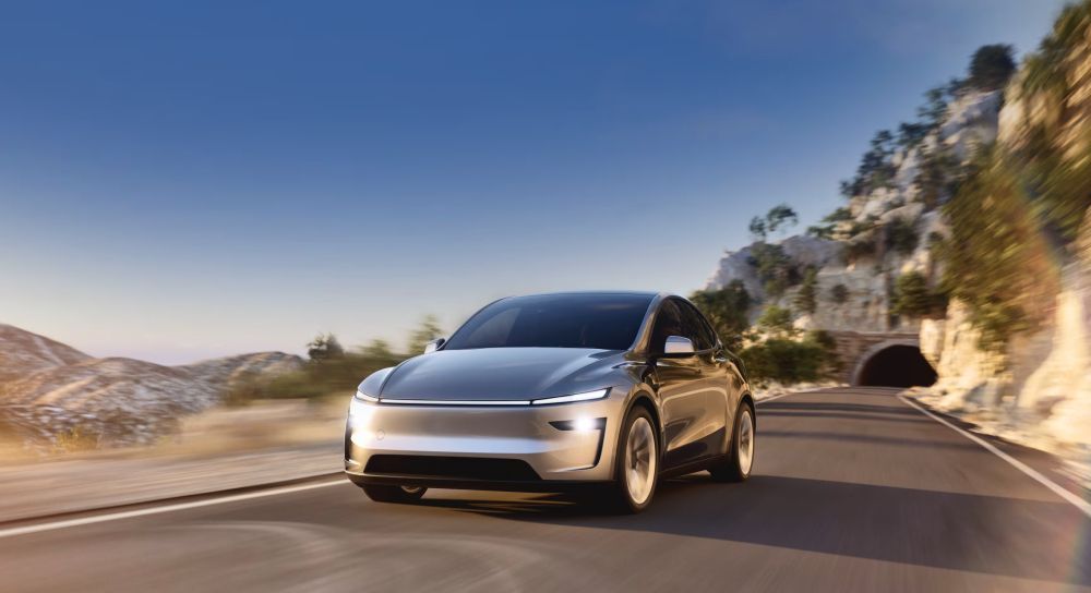 De ge-upgrade Tesla Model Y (2025) rijdt in de bergen met een mooi blauwe lucht op de achtergrond