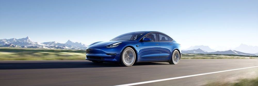 Een blauwe Tesla Model 3 rijdt op de weg