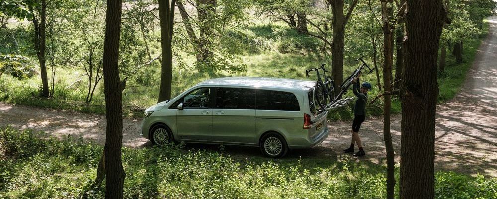 Fietsen worden op een EQV-camper van Tonke gezet die op een bosweggetje staat