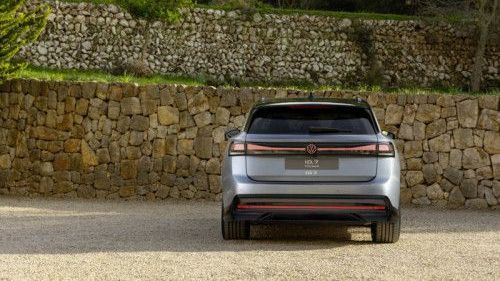 Voor een muur van stenen staat een Volkswagen ID.7 Tourer met de achterkant op de foto