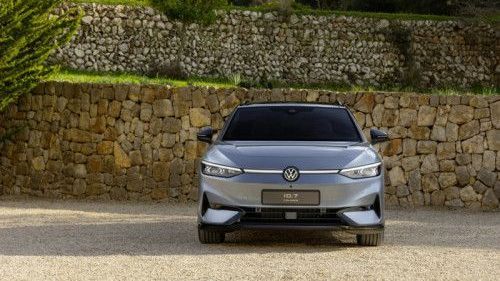 Voor een muur van stenen staat een Volkswagen ID.7 Tourer met de voorkant op de foto