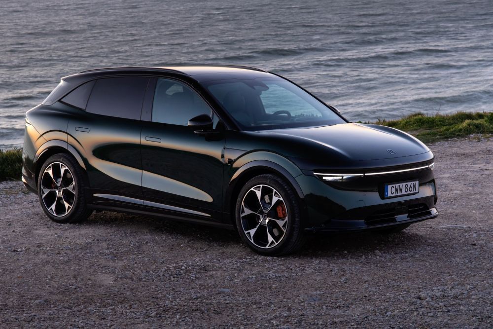 Een donkergrijze Zeekr 7X staat op onverhard terrein aan het water