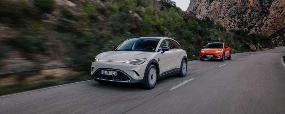 Twee elektrische Smart 3's rijden over een weg door de bergen