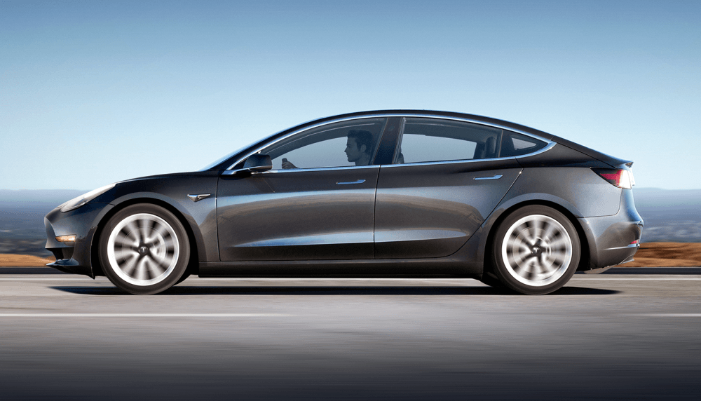 Een donkerkleurige Tesla Model 3 rijdt over de weg