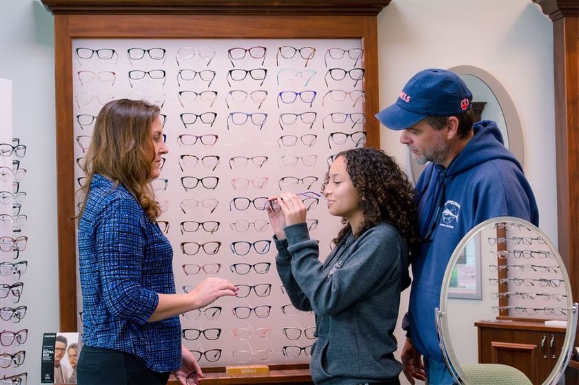 A man, mother and their teenage daughter are shopping for eyeglasses