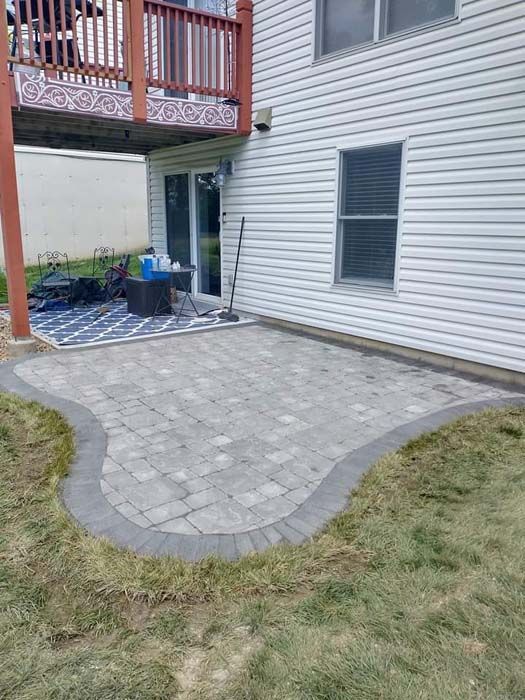 A patio is being built in the backyard of a house.