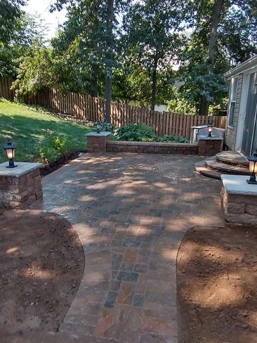 A patio with a wooden fence and trees in the background.
