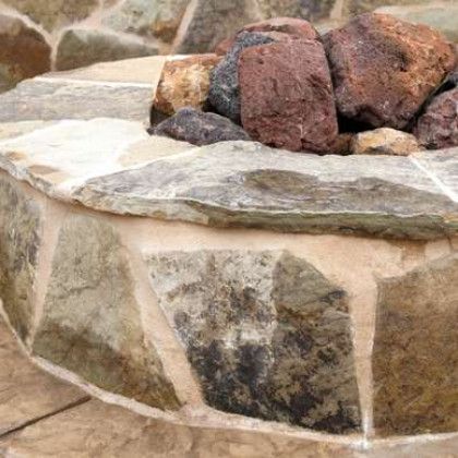 A close up of a stone fire pit with rocks in it.