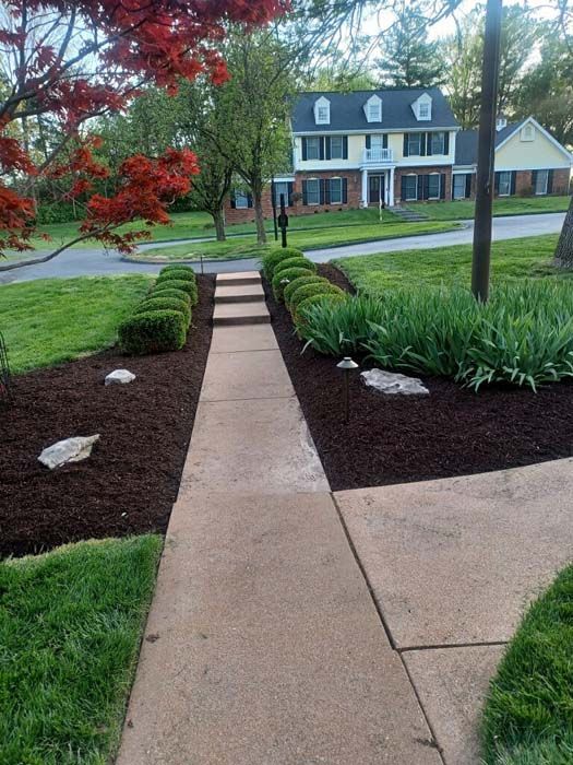 A walkway leading to a house with a brick building in the background