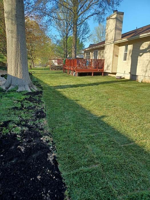 A house with a large lawn and a deck in the backyard.
