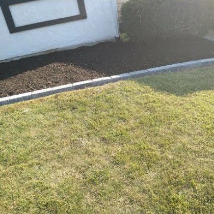 A lush green lawn with a white house in the background.